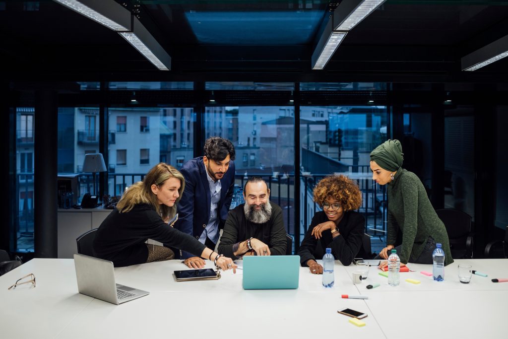 A group of five diverse people is collaborating in a meeting room.
