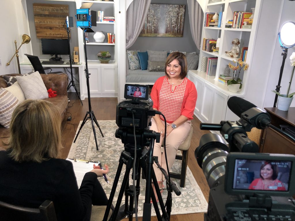 A video filming setup in a living room with lights, cameras, and microphones.