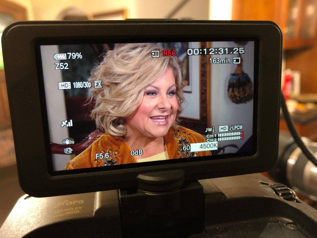 A camera screen showing a blonde woman doing an interview.