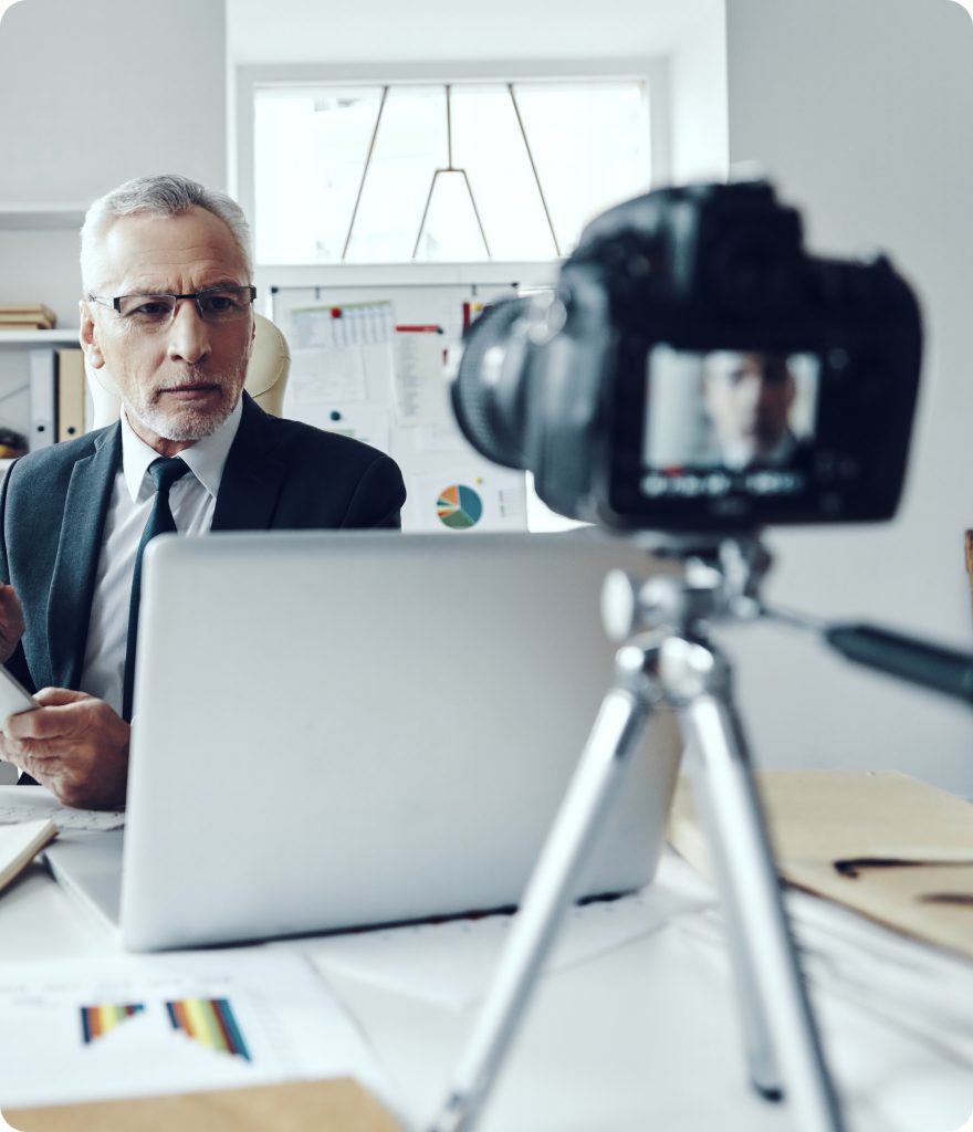 A businessman is being filmed while he is at his work desk.