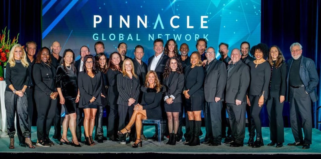 The Pinnacle Global Network Group is taking a team photo on stage.