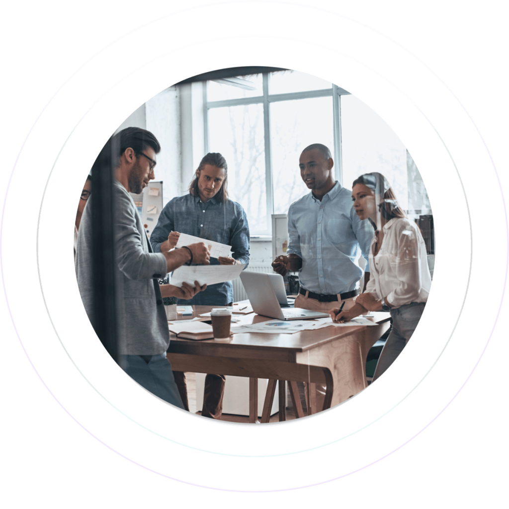 Five corporate employees are discussing in a boardroom with glass walls.