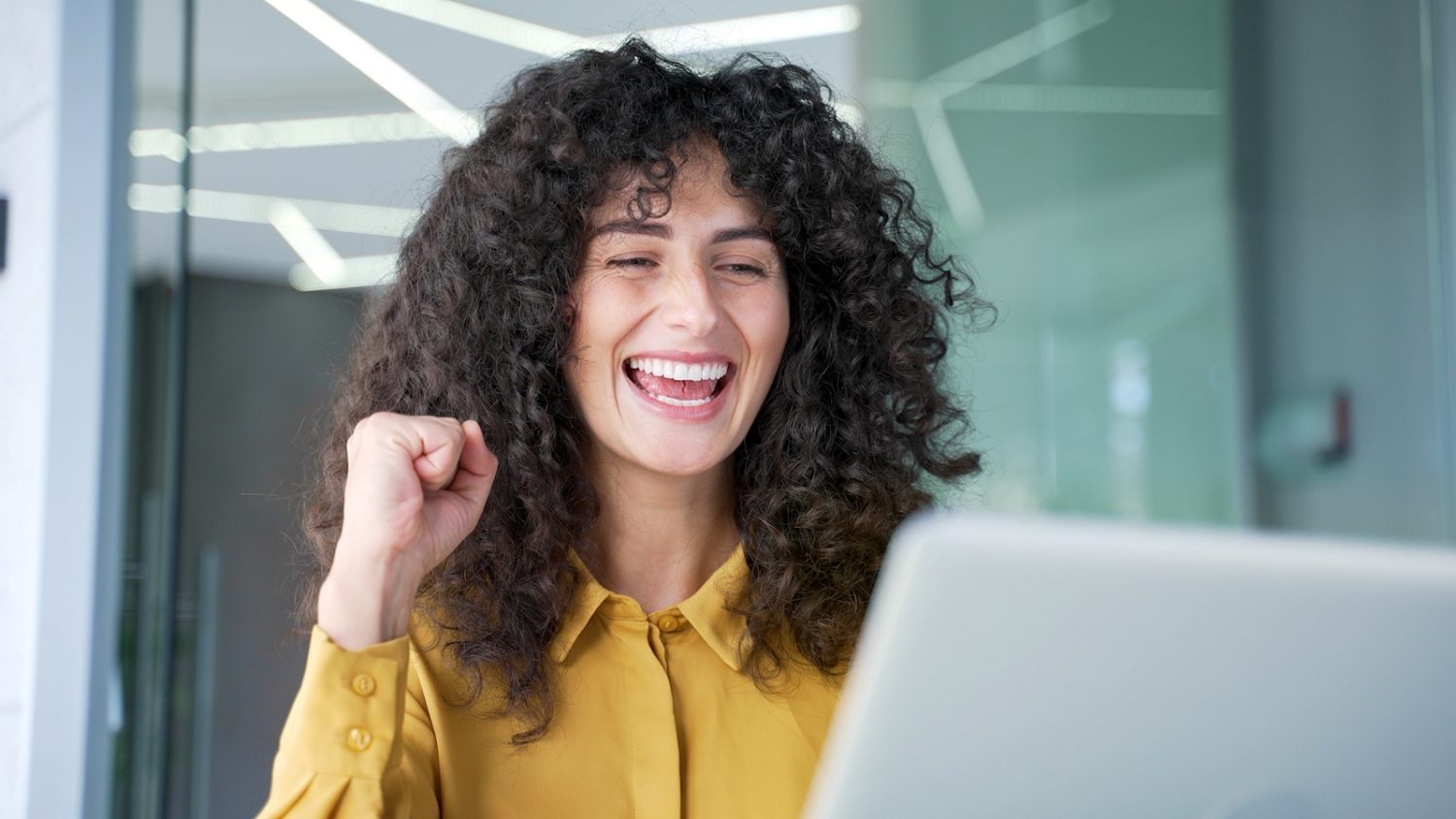 A female business owner shows excitement about the success of her digital paid ads campaign.